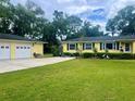 Charming yellow home with green shutters and well-manicured lawn, complemented by a detached garage and ample parking at 3321 Meander Ln, Safety Harbor, FL 34695