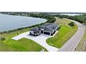 Wide aerial view of a landscaped modern home with a lake backdrop near a paved road at 3610 Gulf City Rd, Ruskin, FL 33570