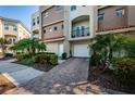 A multi-level townhouse with a brick-paved driveway and meticulous landscaping showcasing palm trees at 805 100Th N Ave, St Petersburg, FL 33702