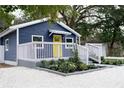 Exterior view of the home with blue siding, white trim, yellow front door, white rock ground cover, and landscaping at 8303 N 17Th St, Tampa, FL 33604