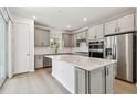 A spacious kitchen featuring gray cabinets, stainless steel appliances, a kitchen island with a white countertop, and a sliding glass door at 9535 Coastline Way, Parrish, FL 34219