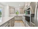 Modern kitchen featuring stainless steel appliances, gray cabinetry, a white backsplash, and a kitchen island with a cooktop at 9535 Coastline Way, Parrish, FL 34219