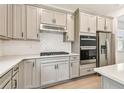 Modern kitchen with stainless steel appliances, gray cabinets, a white subway tile backsplash, and a cooktop on the counter at 9535 Coastline Way, Parrish, FL 34219