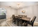 A formal dining room featuring wood floors, gray walls, chandelier and an adjacent kitchen area at 10308 Boyette Creek Blvd, Riverview, FL 33569