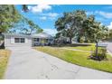 Pleasant home with a spacious front yard, mature trees, and a long driveway, showcasing curb appeal at 1422 Pinebrook Dr, Clearwater, FL 33755