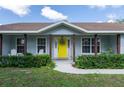 Inviting front entrance featuring a bright yellow door, well-kept lawn, and established landscaping at 206 147Th E St, Bradenton, FL 34212