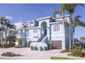 Beautiful light blue two-story home boasts a two-car garage, brick driveway, and staircase to the front door at 2111 Alexis Ct, Tarpon Springs, FL 34689