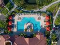 Aerial view of an inviting community pool area with ample seating and umbrellas at 2741 Via Cipriani # 931A, Clearwater, FL 33764