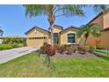 Beautiful yellow house featuring well-maintained landscaping and a paved driveway leading to the garage at 336 Silver Falls Dr, Apollo Beach, FL 33572