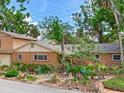 A charming brick home featuring a colorful front yard garden with whimsical decorations and stone accents at 402 S Barbara Ln, Tampa, FL 33609