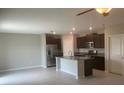 Modern kitchen with stainless steel appliances, island with sink and dark cabinetry at 5511 Rainwood Meadows Dr, Apollo Beach, FL 33572