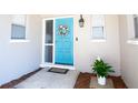 Inviting blue front door adorned with a wreath, flanked by windows and a potted plant at 10035 82Nd St, Seminole, FL 33777