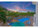 Bright, beautiful pool area featuring lounge chairs, tables, umbrellas, and a jacuzzi with lush tropical landscaping at 11605 Gulf Blvd # 203, Treasure Island, FL 33706