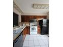 Updated kitchen featuring wood cabinetry, white appliances, neutral countertops, and a double basin sink at 13813 Mission Oaks Blvd, Seminole, FL 33776