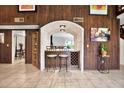 Charming wet bar featuring a brick arch, wood paneling, and seating for two at 13902 Bardmoor Pl # B, Tampa, FL 33618