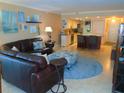 Living room with leather sofa and ottoman flowing into the kitchen and dining area at 15400 Gulf Blvd # 502, Madeira Beach, FL 33708