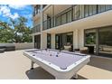 Spacious outdoor patio with pool table, seating, and sliding glass doors to luxurious condo at 220 Belleview Blvd # 104, Belleair, FL 33756