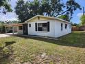 A cozy single-story white house with black shutters on a sunny day with a green yard at 6012 Frond Way, Apollo Beach, FL 33572