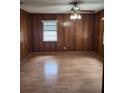 Traditional living room with hardwood floors, wood paneled walls, and a large window for natural light at 6012 Frond Way, Apollo Beach, FL 33572