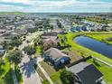 An aerial view of a residential neighborhood featuring houses, green spaces, and a beautiful pond at 10540 Carloway Hills Dr, Wimauma, FL 33598