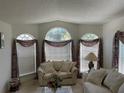 Bright living room with large windows, comfortable seating, and soft natural light at 11185 Heathrow Ave, Spring Hill, FL 34609