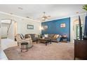 Comfortable living room with a ceiling fan, plush carpeting, and a striking blue accent wall at 11519 Cypress Reserve Dr, Tampa, FL 33626