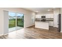 Open kitchen with white cabinets, island, stainless steel appliances, and sliding glass doors to a backyard at 13034 Wellspring Dr, Lithia, FL 33547