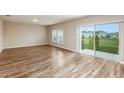 Open concept living area with neutral walls, wood flooring and sliding glass doors leading to the backyard at 13034 Wellspring Dr, Lithia, FL 33547