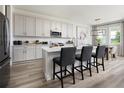 A bright kitchen features white cabinets, a quartz countertop island with chairs, and stainless steel appliances at 14423 Meadow Bird Ave, Riverview, FL 33579