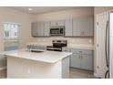 A modern kitchen with gray cabinets, stainless steel appliances, and a center island with a sink at 14811 Summer Branch Dr, Lithia, FL 33547