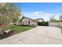 Single-story home with an expansive driveway and partial privacy fence, complemented by a bench and mature trees at 2906 Beagle Pl, Seffner, FL 33584