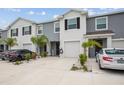Two-story townhome featuring gray and white exterior paint, a driveway, and lush landscaping at 33083 Frosted Clover Way, Wesley Chapel, FL 33545