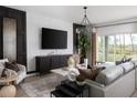Stylish living room with a modern chandelier, a large TV, and comfortable seating at 37073 Sagemoor Dr, Zephyrhills, FL 33541