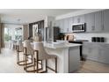 Modern kitchen with gray cabinets, stainless steel appliances, and a large island with seating at 37128 Sagemoor Dr, Zephyrhills, FL 33541