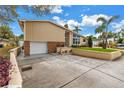 Exterior shot showing the garage and driveway, complemented by manicured landscaping and a partially cloudy sky at 6630 Gulfport S Blvd, South Pasadena, FL 33707
