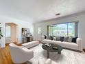 Bright living room with hardwood floors, white walls, modern furniture, and a large window overlooking the neighborhood at 6920 Bougainvilla S Ave, St Petersburg, FL 33707