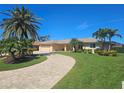 Inviting single-story home featuring a circular paver driveway and lush tropical landscaping at 781 Binnacle Point Dr, Longboat Key, FL 34228