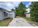 Driveway leading to a fenced backyard, surrounded by trees and greenery at 10275 117Th Dr, Largo, FL 33773