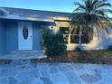 Close-up view of a front door with stone walkway, landscaping, and palm tree at 11096 117Th Way, Seminole, FL 33778