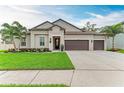 Charming home featuring a three-car garage, a well-maintained lawn, and mature palm trees at 13034 Bliss Loop, Bradenton, FL 34211