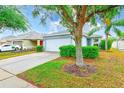 Beautiful single-story home with a well-manicured lawn, lush landscaping, and attached garage at 15410 Quail Woods Pl, Ruskin, FL 33573