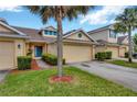 Well-kept townhome with an attached garage, green lawn, and complemented by a tree at 20305 Oak Key Ct, Tampa, FL 33647