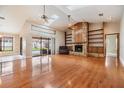 Spacious living room with hardwood floors, a stone fireplace with built-in shelves, and a ceiling fan at 2664 Frisco Dr, Clearwater, FL 33761