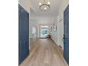 Bright foyer with light wood floors, chandelier lighting, and a view of the pool in the back at 3728 Cypress Meadows Rd, Tampa, FL 33624
