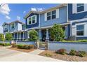 Beautiful blue townhome featuring a landscaped yard and a charming entrance with stone accents and lush greenery at 414 Finn Way # 4, Dunedin, FL 34698