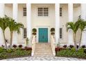 Elegant front entrance with a striking teal door, complimented by manicured landscaping and stately columns at 6106 Marbella Blvd, Apollo Beach, FL 33572