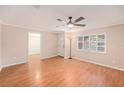 Cozy living room with laminate floors, white plantation shutters on windows, and a door leading to other rooms at 6408 Bonnie Bay N Cir, Pinellas Park, FL 33781