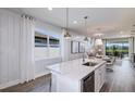 Bright, modern kitchen features a marble island, stainless steel appliances, and a view to the outdoor dining area at 9408 Coastline Way, Parrish, FL 34219