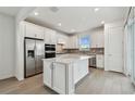 Bright kitchen featuring a large island, stainless steel appliances, white cabinets, and a sliding glass door at 9530 Coastline Way, Parrish, FL 34219