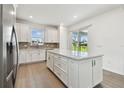 Bright kitchen featuring a center island, stainless steel appliances, white cabinets, and a sliding glass door at 9530 Coastline Way, Parrish, FL 34219